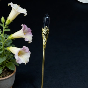 Detail of a vintage golden hair pin featuring a faceted deep blue crystal and filigree