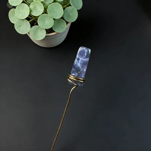 Detail of handcrafted gold wire wrapped blue fluorite crystal pick on black background