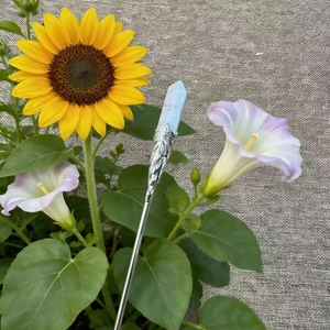 Detail of leaf-embossed silver hair pin with light blue crystal set in a nature scene