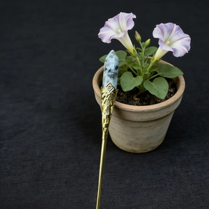Detailed view of an ornate vintage hair pin with light blue natural stone and gold filigree