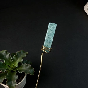 Detail of green crystal stone wrapped in gold wire for decorative plant stakes