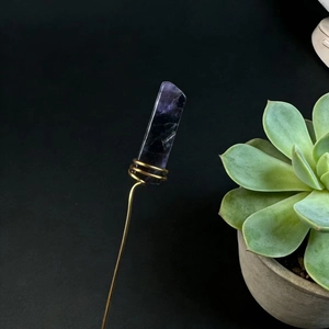 Detail of handmade natural purple crystal fixed with gold copper wire on a long metal stem