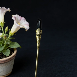 Macro shot of gold floral metalwork and black hexagonal crystal on a vintage hair pin