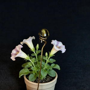 Detail of tiger eye crystal mushroom stake with twisted gold wire in a flower pot