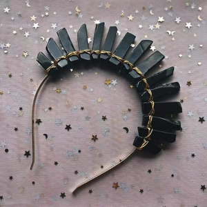 Détail de pierres de cristal noir enroulées à la main avec du fil doré sur un serre-tête