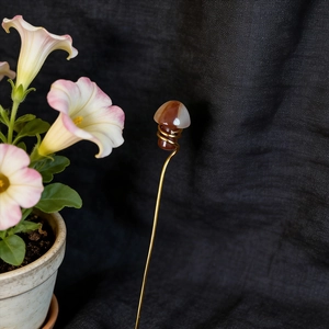 Macro detail of natural agate mushroom ornament with gold wire wrapping for plant decor