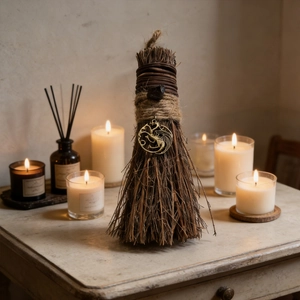 Close-up of handmade decorative witch broom with dragon charm and rustic twine wrap