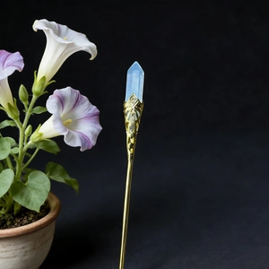 Detail of a gold-tone hair stick with a hexagonal blue crystal and intricate carving