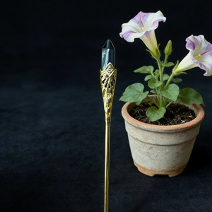 Detail of vintage gold hairpin with black hexagonal crystal and ornate hollow carving
