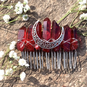 Detail of red crystal moon hair comb with intricate silver wire wrapping on rock background
