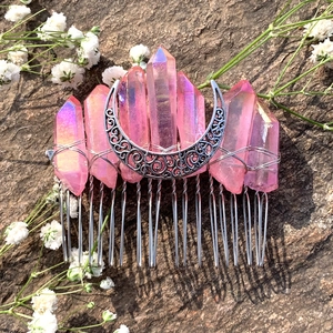 Detail of pink aura crystal moon hair comb with silver wire wrap on dark stone background