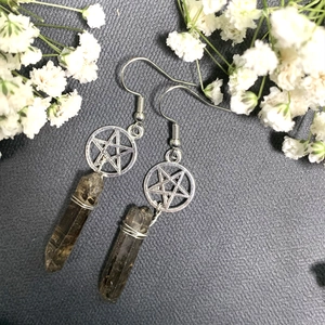 Detail of bohemian silver star earring with smoky crystal point on grey fabric