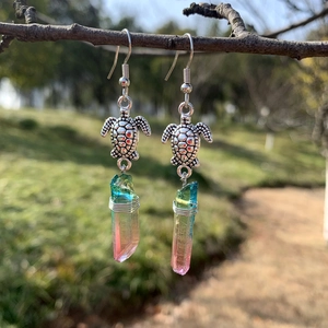 Detail of sea turtle crystal earrings hanging on a branch with colorful quartz stones