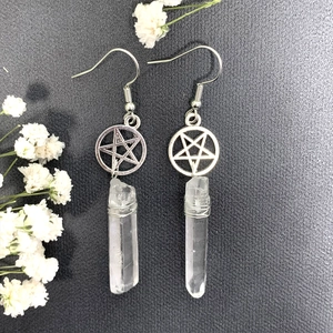Detail of silver pentagram earrings with natural clear quartz crystal pillars on grey background