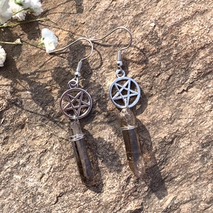 Detailed shot of bohemian pentagram earrings with raw smoky quartz on a stone surface
