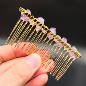 Handmade golden hair comb with natural amethyst stones and white pearls on black background