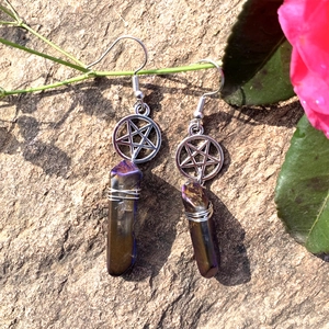 Detail of bohemian star earrings with natural crystal stones hanging on a green stem
