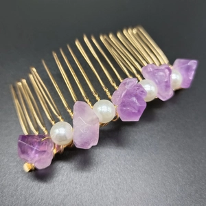 Close-up of handmade purple amethyst hair comb with golden wire and pearl details
