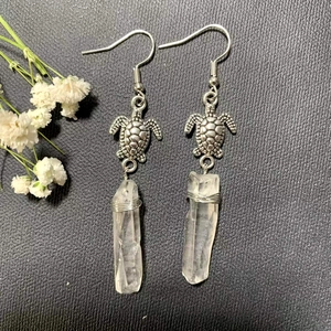 Macro detail of turtle earrings with natural white crystal quartz and silver hooks