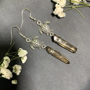Detail of silver turtle earrings with smoky quartz stone and wire-wrapped craft