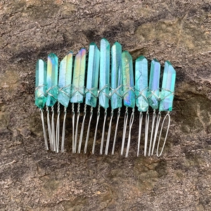 Detail of bohemian teal crystal hair comb with iridescent finish on a natural rock surface