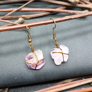 Detailed macro of handmade copper wire-wrapped natural amethyst earrings on wood