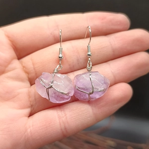 Detail of natural raw amethyst stone earrings with silver wire wrapping and fish hooks