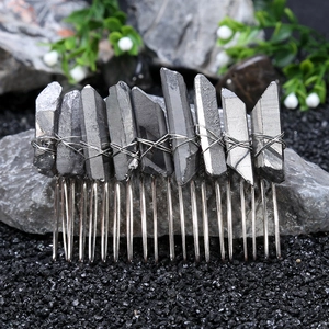 Macro shot of grey raw crystal stones hand-wrapped with silver wire on metal hair comb