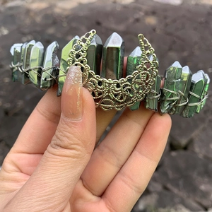 Detail of handmade green crystal crown featuring golden moon and silver wire wrapping