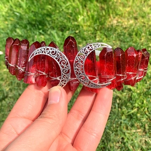 Détail d'une couronne en cristal rouge avec croissants de lune argentés sur fond naturel