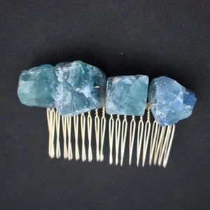 Dettaglio di pietre di cristallo naturale avvolte in filo dorato su un pettine per capelli