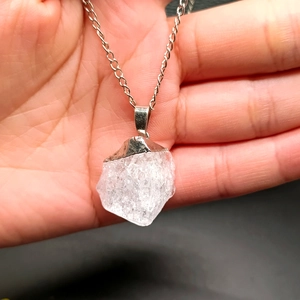 Natural white crystal pendant necklace with silver chain shown in hand for scale