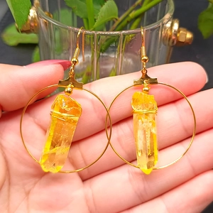 Close-up of bohemian gold hoop earrings with natural yellow crystal pillars on ear hooks