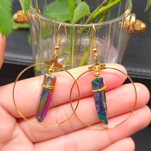 Detail of bohemian gold hoop earring featuring rainbow aura quartz crystal wrapped in wire