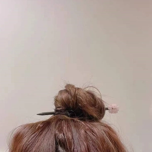 Detail view of a pink cherry blossom hair pin styled in a bun with natural amethyst stones