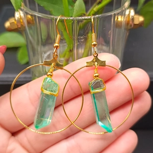 Detailed close-up of bohemian gold hoop earrings with green hexagonal crystal pendants