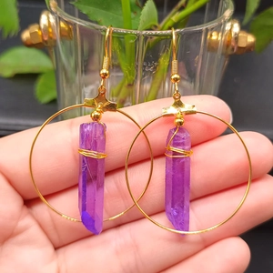 Detail of bohemian gold hoop earrings featuring raw purple crystal pillars and wire wrapping