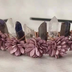 Detailaufnahme handgefertigter Quarzkristallsäulen und Stoffblumen auf einem Stirnband