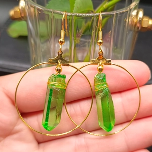 Detailed view of bohemian gold hoop earrings featuring green crystal pendants and wire wrap