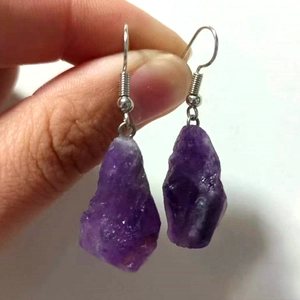 Nahaufnahme von Roh-Amethyst-Ohrhängern mit silbernen Metallhaken, in der Hand gehalten