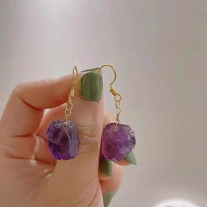 Nahaufnahme von handgefertigten Gold-Ohrringen mit natürlichen lila Amethyst-Steinen
