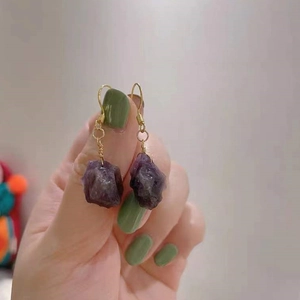 Makro-Detail handgefertigter Amethyst-Ohrringe mit goldenem Drahtwickel-Design