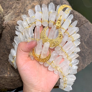 Detail of handmade white crystal crown with gold moon charm on natural rock background
