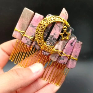 Close-up of pink crystal stone hair comb with golden moon and star pendant charms