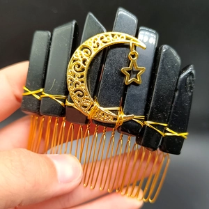 Detail of handmade gold hair comb featuring black crystals and star moon charms