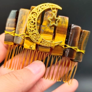 Detailed close-up of tiger eye stone slices with gold crescent moon and star on hair comb