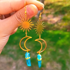 Détail de boucles d'oreilles soleil et lune avec cristaux bleus à la lumière naturelle
