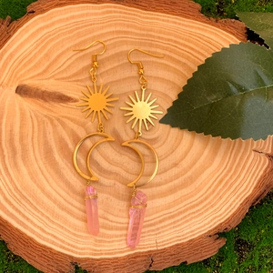 Détail des boucles d'oreilles soleil et lune dorées avec pendentifs en cristal rose