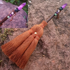 Mystic witch broom car charm with purple crystal point and colorful beads on rock background