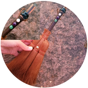 Handcrafted witch broom car charm with natural crystals and red rope on rocky background